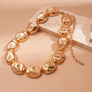 Chunky gold chain necklace featuring irregular crumpled texture blocks on a stone