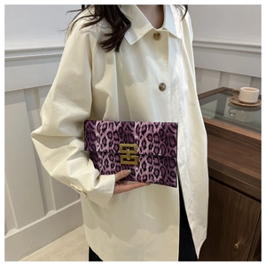 Detail of purple leopard print rectangular clutch with gold metal buckle held by a model