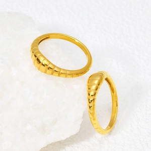 Bague croissant en titane doré avec texture striée sur fond de pierre minérale blanche