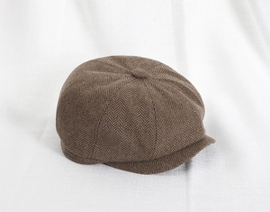 Dettaglio di un cappello da strillone marrone con classico motivo a spina di pesce