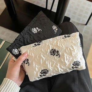 Detail of quilted canvas makeup bags with rose embroidery in black and white styles