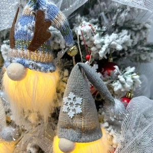 Close-up of glowing Christmas gnomes with reindeer antlers and snowflake knit hats