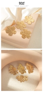 Detail of gold-plated ginkgo and daisy floral charms with hammered texture and matte finish
