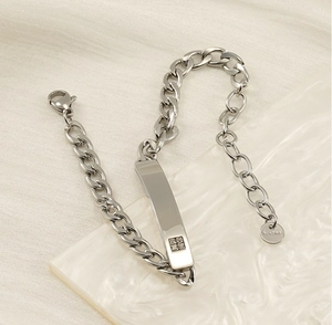 Dettaglio ravvicinato di un bracciale a maglia cubana in acciaio con placca diamantata
