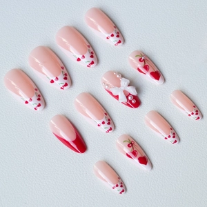 French press-on nails with cherry heart patterns, pearls, and 3D white bows on nude pink