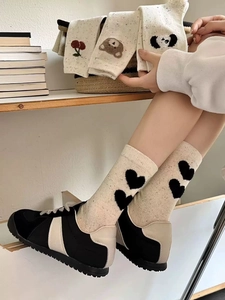 Detailed close-up of knitted crew socks with cute bear, heart, and cherry patterns