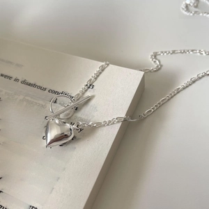 Detailed macro view of silver heart pendant with Figaro chain and vintage toggle clasp