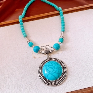 Macro detail of vintage turquoise bead necklace with a round carved silver pendant