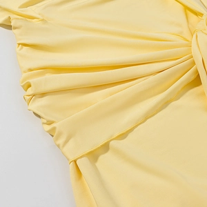 Gros plan d'une robe en maille jaune avec nœud élégant et détails de plis souples