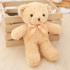 Detail of light brown teddy bear plush with curly fur and orange satin bow in a wooden basket
