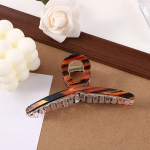 Detailed view of amber striped hair claw clip on a minimalist aesthetic background