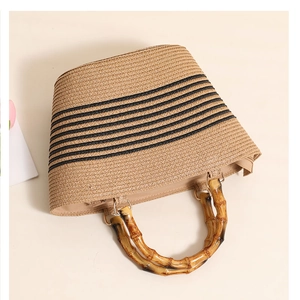 Detail of striped straw handbag with bamboo handle and natural woven texture