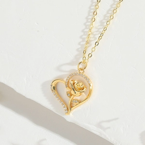 Detailed macro view of heart and rose pendant with sparkling crystals on gold chain