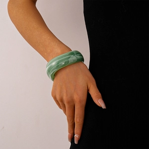 Macro shot of green marble texture acrylic bangle on model with black clothing