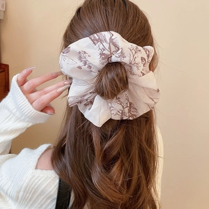 Detail view of a large vintage floral scrunchie on a bun with french style patterns