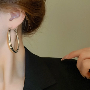 Close-up of a large silver hoop earring on a model in a black suit for a modern look