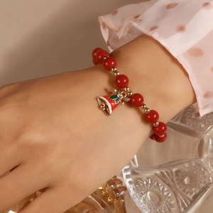 Detail of red Christmas beaded bracelet with golden spacers and festive bell charm on wrist