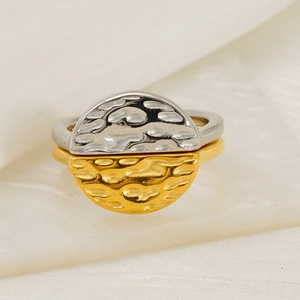 Two-tone silver and gold stainless steel ring with hammered texture on white silk