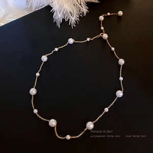 Elegant 18K gold chain pearl necklace with white round pearls on black texture