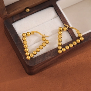 Golden stainless steel beaded V-shape hoop earrings on a dark wooden jewelry gift box