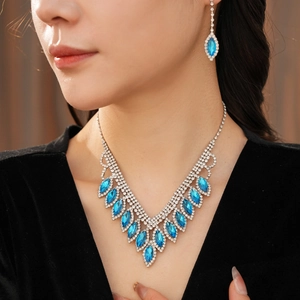 Close-up of blue teardrop pendant necklace and matching diamond earrings on model