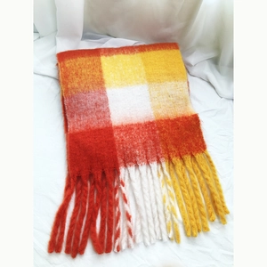 Close-up detail of orange and yellow checkered scarf with soft tassel fringe edges