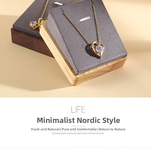 Detail of gold heart pendant necklace with crystal inlay on wooden jewelry display stand