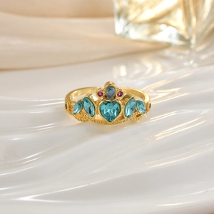 Macro detail of golden crown ring with blue heart stones and red gemstone accents