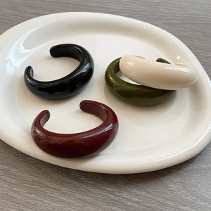 Minimalist resin C-shaped open bangles in assorted retro colors on a white plate