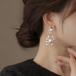 Detail of round pearl drop earrings with gold settings worn by a model in profile view