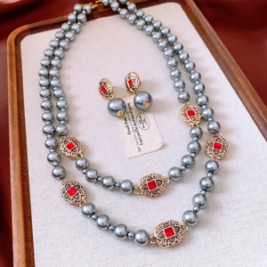 Vintage jewelry set with oval blue pearls and red gemstones on a wooden tray