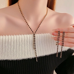 Close-up of elegant gold Y-necklace and long tassel earrings with black gemstones