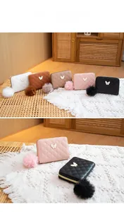 Close-up of quilted PU leather wallets with butterfly hardware and faux fur pompom charms