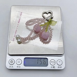 Detail shot of a sweet crystal cherry keychain weighing 15.6g on a digital scale