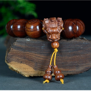 Détail des perles en bois de rose brun foncé avec bête mythique sculptée et pendentifs
