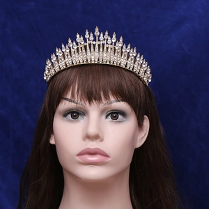 Elegant gold bridal tiara with sparkling rhinestones on a model against blue background