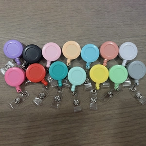 Flat lay of colorful ABS retractable badge reels with metal belt clips on wood background