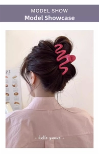 Rear view of model wearing a wavy pink shark clip for elegant hair styling