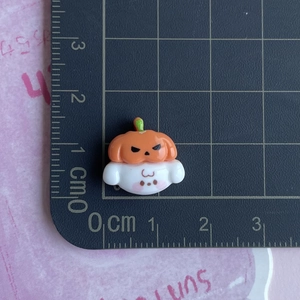 Miniature resin pumpkin ghost charm shown on a centimeter scale ruler for sizing detail