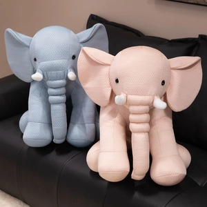 Cute pink and blue soft elephant plush pillows with waffle texture on a leather sofa