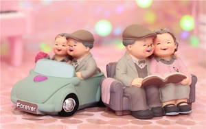 Close-up of resin elder couple figurines sitting in a green car and on a sofa