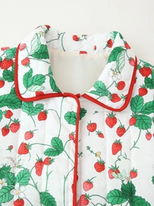 Close-up of quilted floral cotton coat with strawberry print and red piping detail