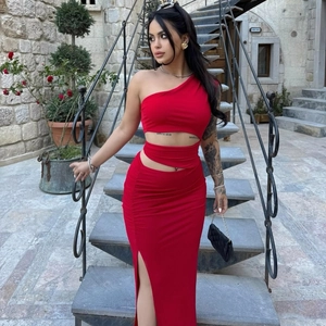 Detail of red one-shoulder cut-out dress with high-slit skirt and ruched fabric texture
