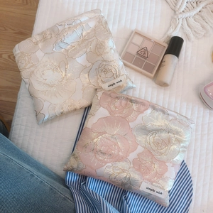 Elegant gold rose jacquard small cosmetic bags with floral patterns on a white bed