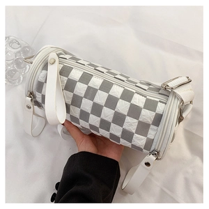 Detail of checkered cylinder bag with leather handles and wide fabric strap