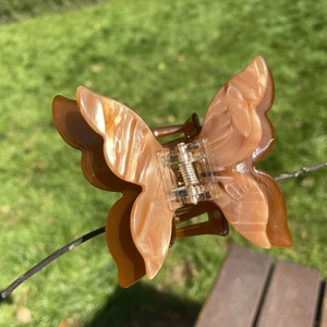 Macro detail of amber acetate butterfly hair claw clip with high gloss finish in sunlight