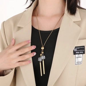 Close-up of a golden Y-shaped long necklace with glass crystal and metallic beads