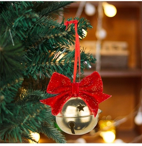 Close-up of red velvet bow with golden bell ornament hanging on a Christmas tree