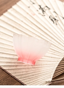 Detail of pink gradient lotus tea cup with petal rim on a traditional folding fan background