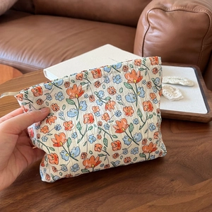 Handheld view of a floral makeup bag with natural wrinkled texture and soft floral print